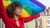 Young woman in red shirt holding a PRIDE flag above her head